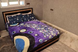 ein Bett mit einer lila Bettdecke und Kissen in der Unterkunft Tidli home in Mirleft