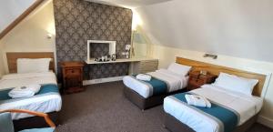 a hotel room with three beds and a mirror at Russell Hotel in Royal Tunbridge Wells
