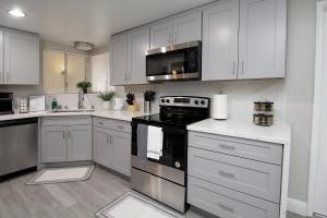 a kitchen with white cabinets and a black stove top oven at Entire Magill House by RiverPark in Fresno