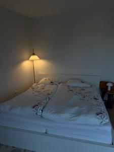 a bed with a white blanket and a lamp at Lejlighed kbh in Copenhagen