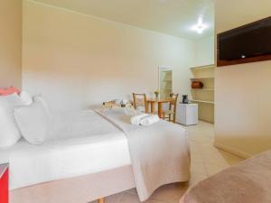 ein Schlafzimmer mit einem großen weißen Bett und einem Fernseher in der Unterkunft Pousada Chaday in Imbituba