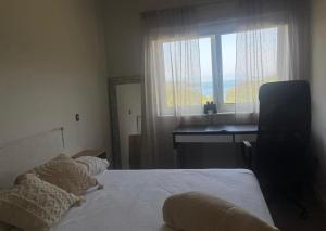 a bedroom with a bed and a desk and a window at A Casa da Moucha in Muxia