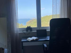 a desk with a laptop and a book in front of a window at A Casa da Moucha in Muxia