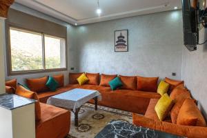 a living room with an orange couch with colorful pillows at Bab Atas appartment N4 in Ourika Valley in Marrakech