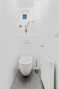 a white bathroom with a toilet and a plant at Comfortable 2 Bedroom Apartment in Vienna