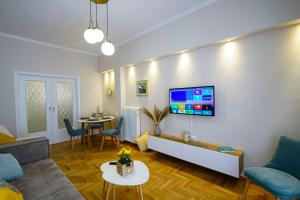 Una sala de estar con un sofá y un televisor en una pared. en central elegant apartment in koukaki,near acropoli, en Atenas