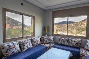 ein Wohnzimmer mit einem blauen Sofa und 2 Fenstern in der Unterkunft Bab Atlas appartment N3 in Ourika valley in Aghbalou + 9 Fotos
