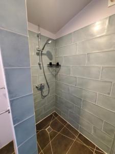 a bathroom with a shower with gray tiles at Cabane du lac in Rouffignac Saint-Cernin
