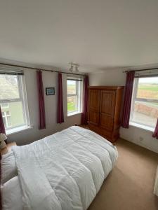 Un dormitorio con una cama blanca y dos ventanas. en Burnett House Flats, en Seascale 5 fotos más