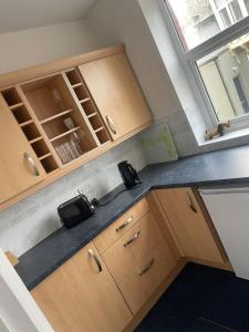 una pequeña cocina con armarios de madera y una ventana en Burnett House Flats, en Seascale
