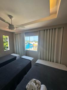 Un dormitorio con dos camas y una ventana. en Arraial Hospedagem, en Arraial do Cabo