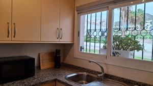 een keuken met een wastafel en een raam met een potplant bij Carmen Casa Helena in Nerja