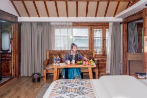 a woman sitting at a table in a bedroom at Walk Together Hotel in Lijiang