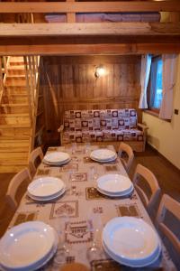 a table with white plates and chairs in a room at Le Nid de l'Aigle in Champoluc