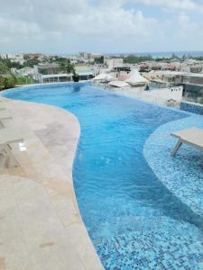 una grande piscina con acqua azzurra di Acogedor Condo a metros de la 5ta Avenida a Playa del Carmen