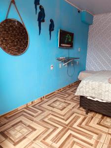 a bedroom with blue walls and a wooden floor at kitnet aconchegante in Ubatuba +9 photos
