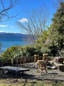 two picnic tables and a bench next to the water at TEROTERO Lake Hostel - Habitación Gutiérrez in San Carlos de Bariloche