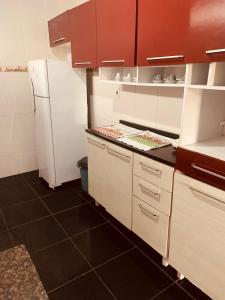 a kitchen with white cabinets and a white refrigerator at kitnet aconchegante in Ubatuba