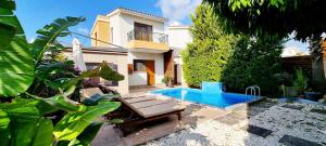 a backyard with a swimming pool and a house at Shanti Paphos Holiday House in Paphos