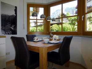 eine Küche mit einem Holztisch mit Stühlen und Fenstern in der Unterkunft Boutiqueferienwohnung Schnapshäusel in Oberstdorf