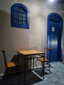 une table et deux chaises à côté d'une porte bleue dans l'établissement Pousada DONA DUTRA, à Lençóis Paulista