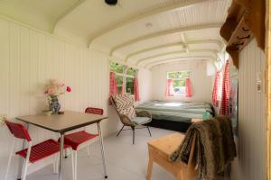 una habitación con una cama, una mesa y sillas en Pipowagen Camping Namasté, en Berlicum