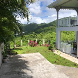 un porche d'une maison avec vue sur une montagne dans l'établissement L'albizia, à Les Anses-d'Arlet