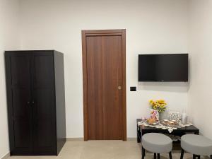a room with a table and a cabinet and a television at Mirea Guest House in Latina