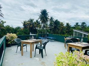 a patio with tables and chairs and palm trees at Villa Mangofera in Galle