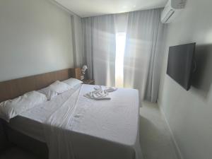 a bedroom with a bed with white sheets and a television at Salinas Exclusive Resort in Salinópolis +54 photos