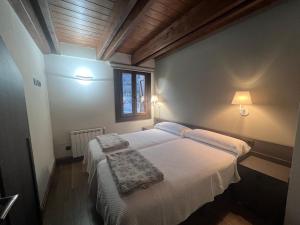 a bedroom with two beds with white sheets and a window at Apartamentos Casa Roldan I in Benasque