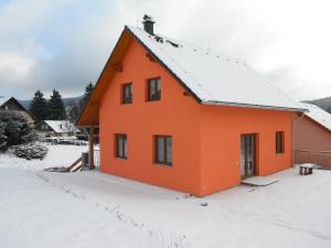 ein orangenes Haus mit Schnee auf dem Boden in der Unterkunft Holiday Home U Fišerů in Kašperské Hory