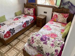 a bedroom with two beds with floral sheets at Dar Nakhla in Chefchaouen