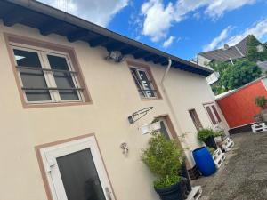 a white house with a door and potted plants at Benk 24H Apartment Nr 2 Perfekt für bis zu 4 Personen in Hofheim am Taunus