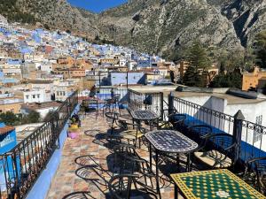 a balcony with tables and chairs and a view of a city at Dar Nakhla in Chefchaouen +64 photos