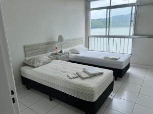 two beds in a room with a window at apartamento sao vicente vista mar pe na areia in São Vicente