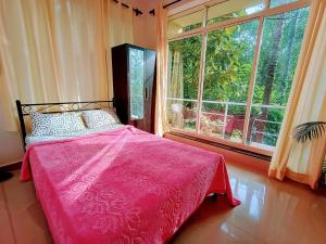 a bedroom with a pink bed and a large window at GS Home on the Bay - Sea & forest view glass studio in Vagator