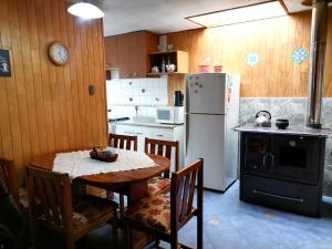 une cuisine avec une table et un réfrigérateur blanc dans l'établissement Acogedora casa en el sur de Chile, ubicada en barrio residencial, à Puerto Montt
