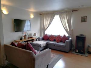 un salon avec deux canapés et une télévision à écran plat dans l'établissement Acogedora casa en el sur de Chile, ubicada en barrio residencial, à Puerto Montt