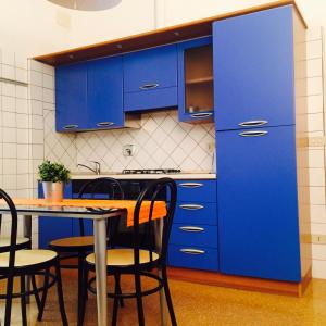 a kitchen with blue cabinets and a table and chairs at Temporary House Oberdan in Bologna