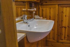 La salle de bains est pourvue d'un lavabo blanc et de placards en bois. dans l'établissement Appartamento Sellaronda, à Arabba 5 autres photos