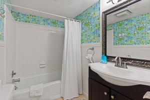 ein Badezimmer mit Waschbecken, Badewanne und Spiegel in der Unterkunft Beachcomber, Unit 302 in Demere Park + 12 Fotos