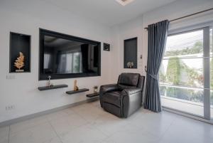a living room with a chair and a large window at Luxury 4 Bedroom Beach House in Ban Saiyuan (1)