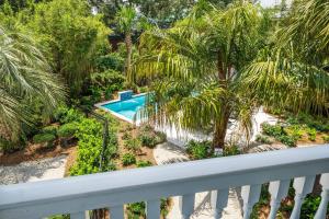 a balcony view of a swimming pool and palm trees at A Wave From It All - 811 Ocean Blvd in Saint Simons