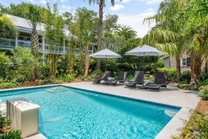 a swimming pool with chairs and umbrellas next to a house at A Wave From It All - 811 Ocean Blvd in Saint Simons