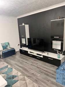 een woonkamer met een grote flatscreen-tv aan een zwarte muur bij Lovely tidy and well decorated en-suite king sized bedroom in a shared 2 bedroom flat in Belle Isle