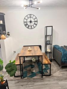 een woonkamer met een tafel en een klok aan de muur bij Lovely tidy and well decorated en-suite king sized bedroom in a shared 2 bedroom flat in Belle Isle