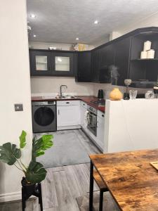 een keuken met zwarte kasten en een tafel met een plant bij Lovely tidy and well decorated en-suite king sized bedroom in a shared 2 bedroom flat in Belle Isle