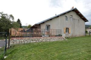 a house with a stone wall and a balcony at La ferme d aumontzey in Aumontzey