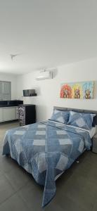 een slaapkamer met een bed met een blauw dekbed bij RC FLAT Studio 05 Tamandaré, à 200m da praia in Tamandaré